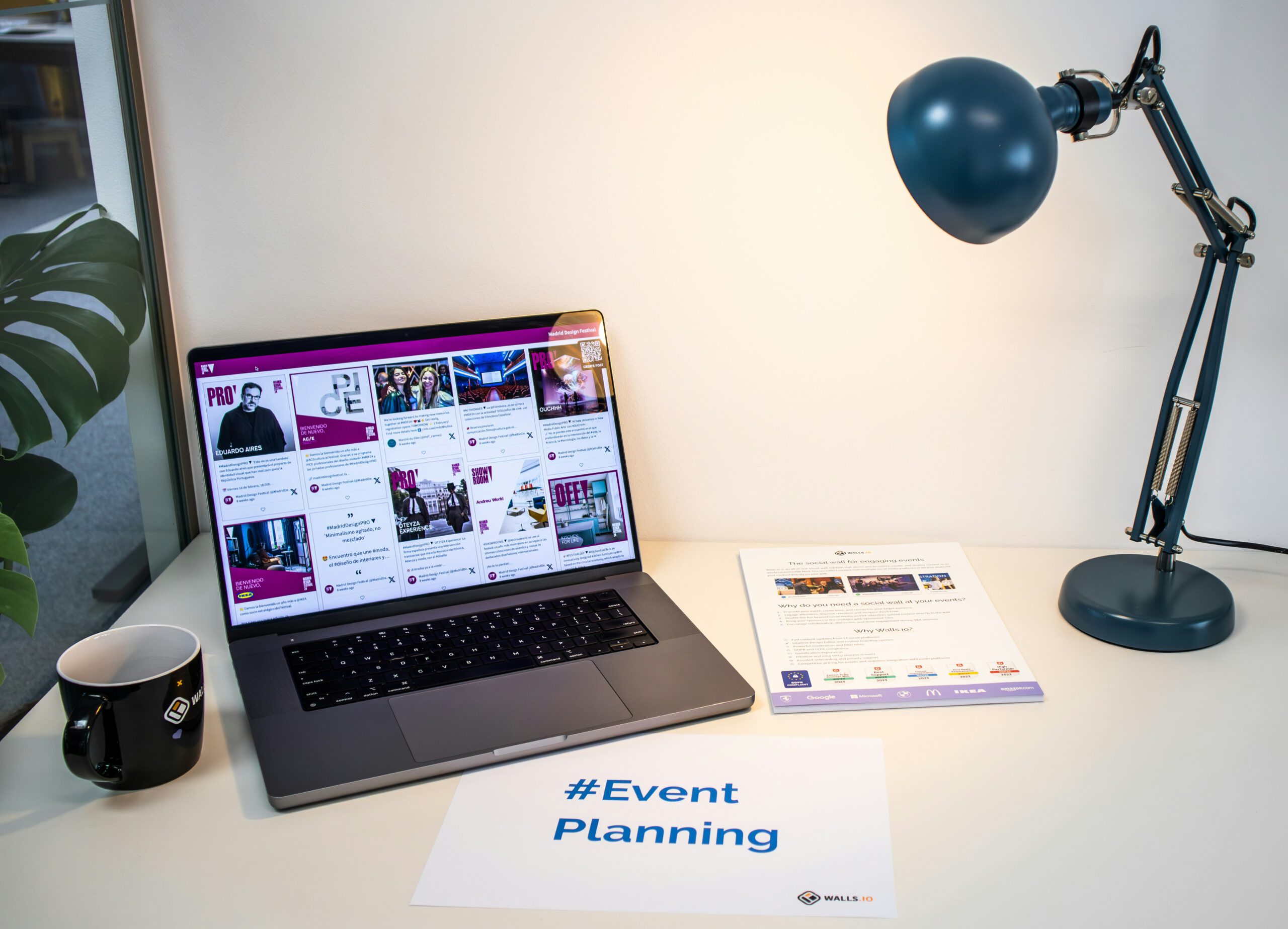 Schreibtisch-Workspace mit Laptop zeigt Social Media Event Planning Dashboard, Kaffeetasse, Schreibtischlampe und Schild mit #Event Planning – digitaler Marketing-Arbeitsplatz